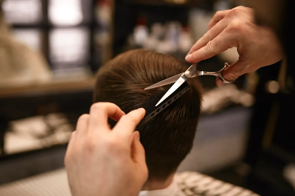 Der Kopf eines Mannes von hinten, der gerade einen Haarschnitt in einem Friseursalon bekommt.